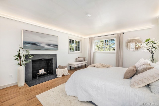 bedroom featuring a fireplace with flush hearth and wood finished floors