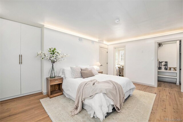 bedroom with baseboards, visible vents, and light wood-style floors