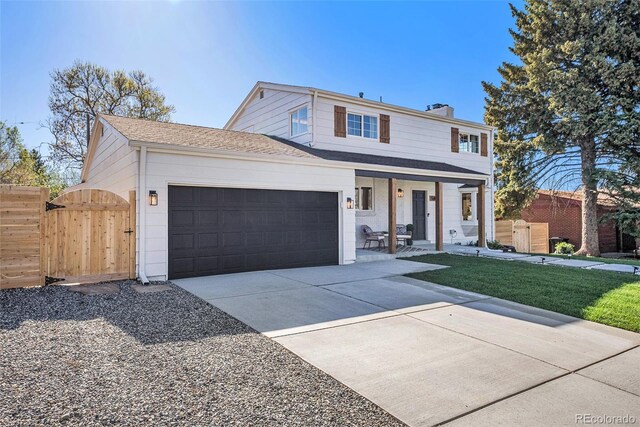 traditional home with fence, an attached garage, concrete driveway, a porch, and a gate
