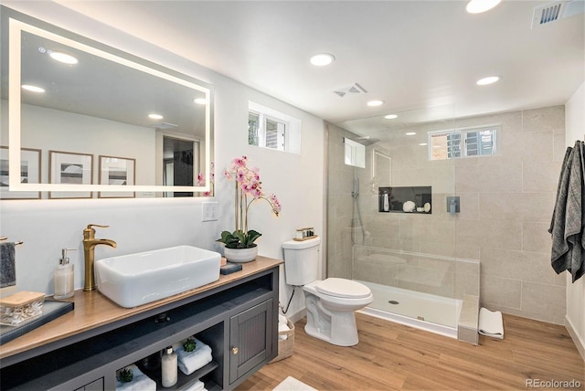 full bathroom with toilet, visible vents, wood finished floors, and tiled shower