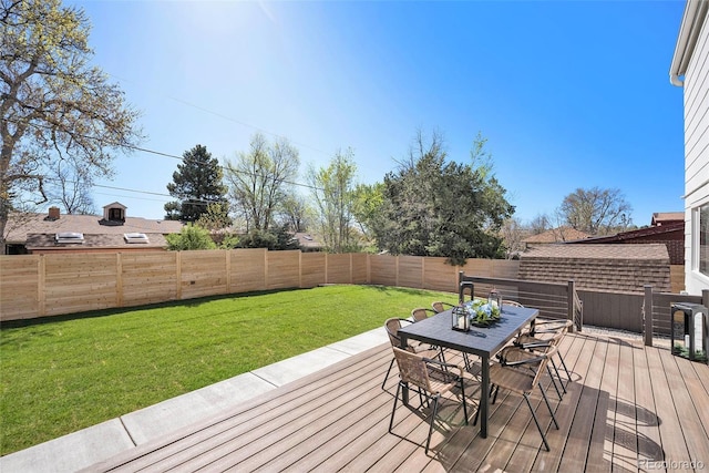 deck with a fenced backyard, outdoor dining area, and a yard