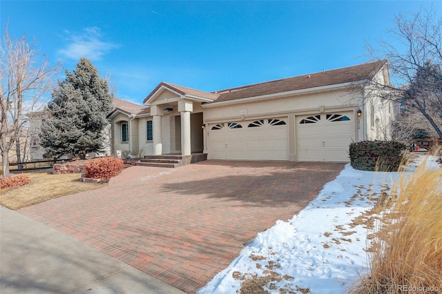 view of front facade with an attached garage, decorative driveway, and stucco siding