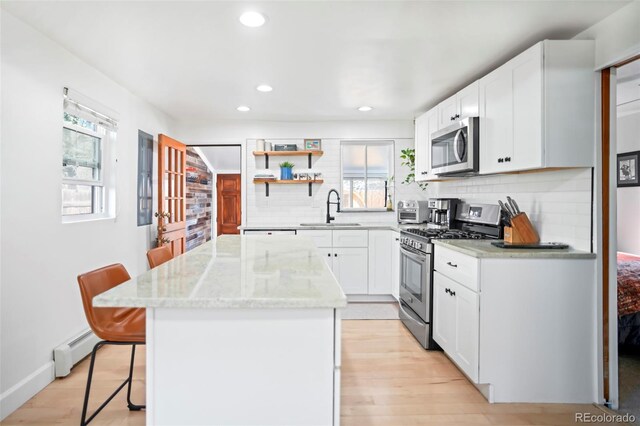 3521 W 40th Ave, Denver, CO 80211 - kitchen featuring stainless steel appliances, a sink, a kitchen island, a baseboard radiator, and healthy amount of natural light