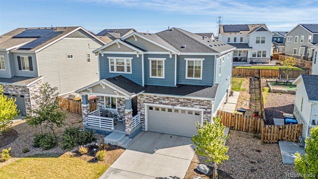 118 N Newcastle Way, Aurora, CO 80018 - view of front of house with an attached garage, stone siding, a residential view, concrete driveway, and fence