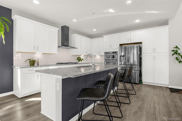 118 N Newcastle Way, Aurora, CO 80018 - kitchen featuring wall chimney exhaust hood, stainless steel appliances, wood finished floors, a sink, and white cabinets