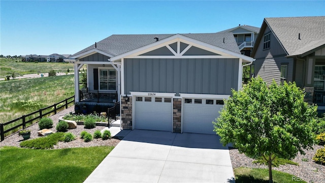 view of front of house featuring board and batten siding, covered porch, driveway, and stone siding