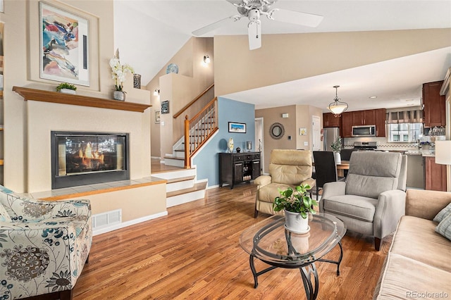 living room with vaulted ceiling, ceiling fan, and light hardwood / wood-style flooring