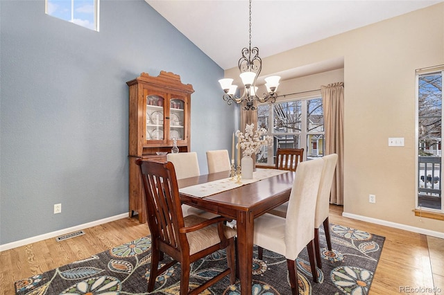 dining area featuring vaulted ceiling, a chandelier, and light wood-type flooring