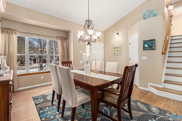 dining area featuring an inviting chandelier, vaulted ceiling, and light wood-type flooring