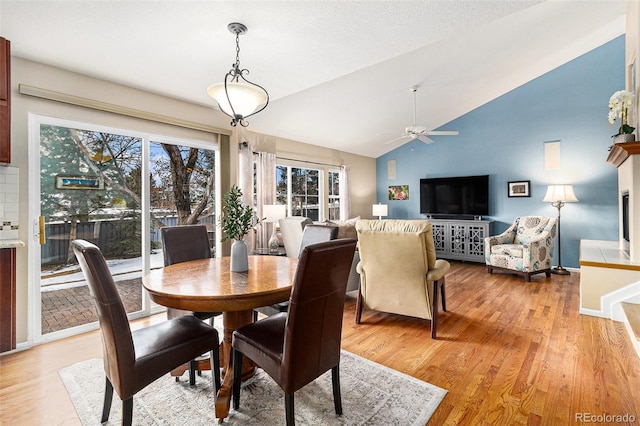 dining space with ceiling fan, lofted ceiling, and light hardwood / wood-style flooring