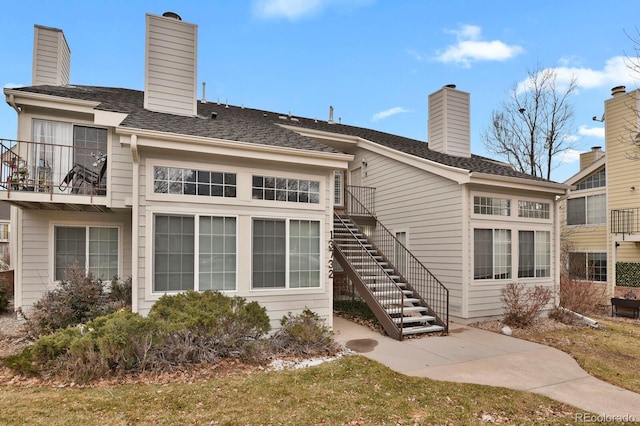 rear view of house featuring stairway, a chimney, and a balcony