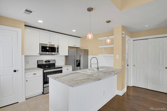 kitchen with stainless steel appliances, a peninsula, a sink, white cabinets, and light wood finished floors