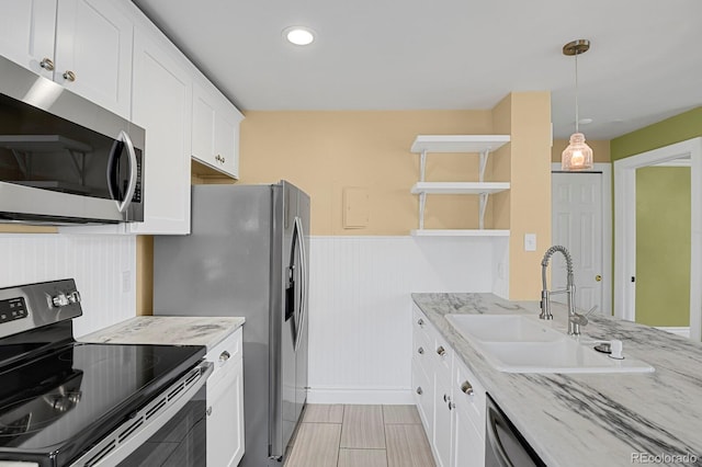 kitchen featuring appliances with stainless steel finishes, light stone countertops, white cabinetry, open shelves, and a sink