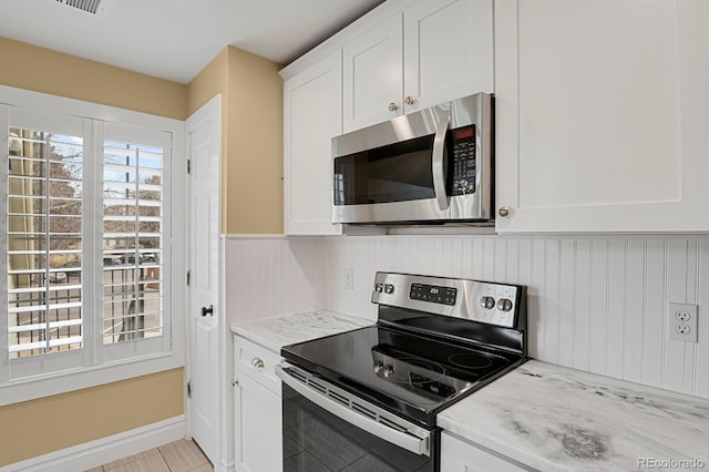 kitchen featuring appliances with stainless steel finishes, white cabinets, and light stone countertops