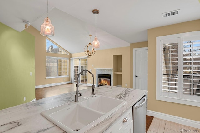 kitchen featuring visible vents, dishwasher, a glass covered fireplace, open floor plan, and a sink