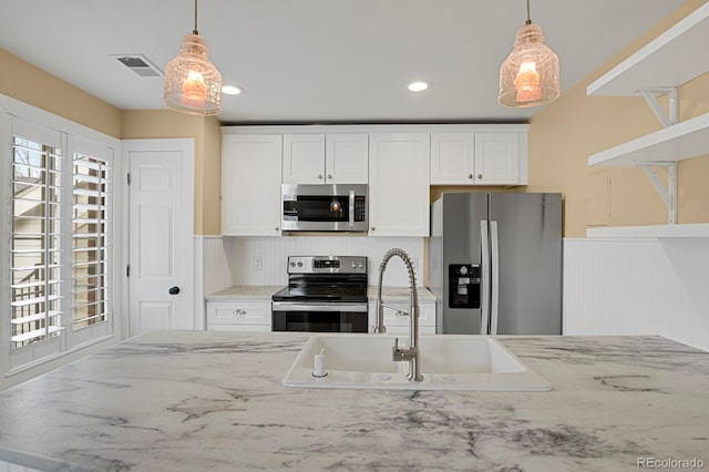 kitchen featuring visible vents, stainless steel appliances, a sink, and pendant lighting