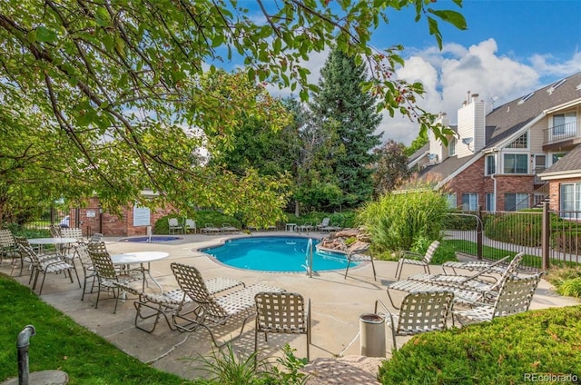 community pool featuring fence and a patio