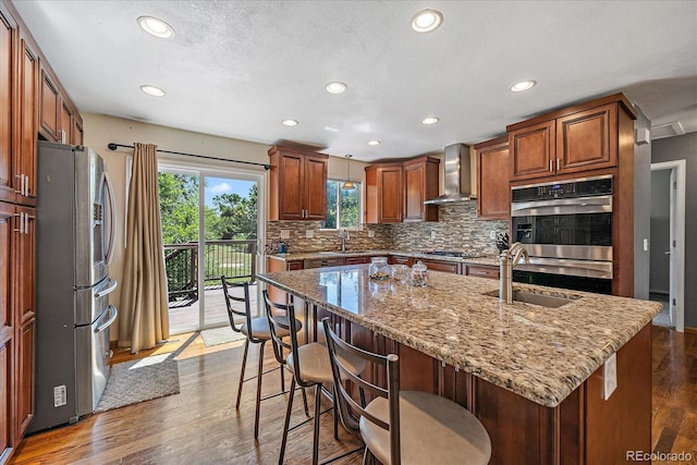10714 Birch Ct, Thornton, CO 80233 - kitchen featuring stainless steel appliances, wall chimney range hood, recessed lighting, light stone countertops, and tasteful backsplash