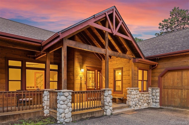 exterior entry at dusk with a porch and a garage