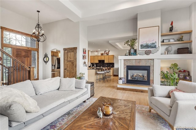 1654 Muirfield Ln, Evergreen, CO 80439 - living area featuring a chandelier, light wood-style floors, a tiled fireplace, stairs, and arched walkways
