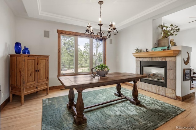 1654 Muirfield Ln, Evergreen, CO 80439 - dining room featuring a raised ceiling, a chandelier, light wood-style flooring, a tiled fireplace, and baseboards