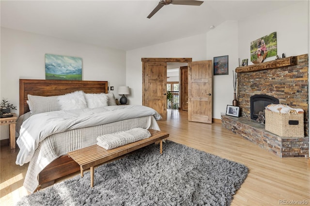 1654 Muirfield Ln, Evergreen, CO 80439 - bedroom featuring vaulted ceiling, wood finished floors, a stone fireplace, and a ceiling fan