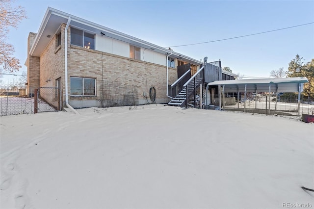 snow covered house featuring a carport