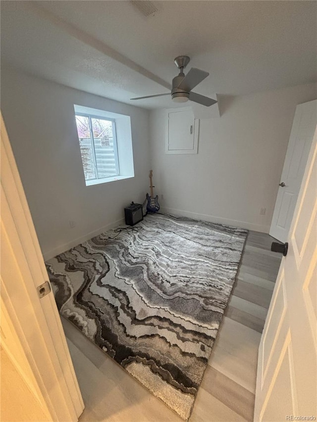 spare room featuring baseboards, wood finished floors, and a ceiling fan