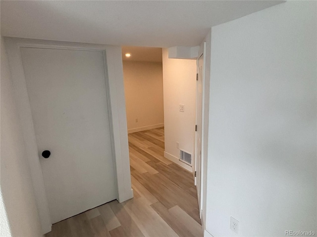 corridor featuring baseboards, light wood-style flooring, and visible vents