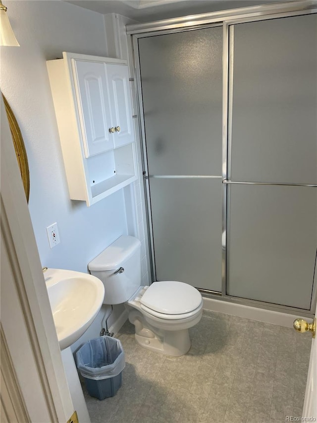bathroom with a sink, toilet, and a shower stall