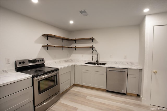 201 Monmouth Ave, Firestone, CO 80520 - kitchen featuring appliances with stainless steel finishes, a sink, gray cabinetry, light wood-style floors, and light stone countertops