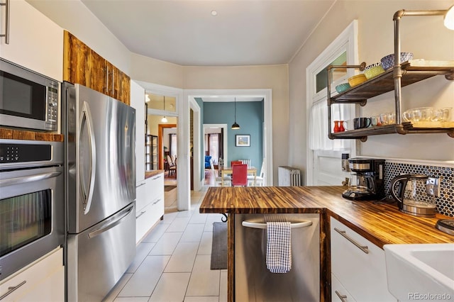 1437 Columbine St, Denver, CO 80206 - kitchen featuring stainless steel appliances, wood counters, light tile patterned flooring, white cabinetry, and open shelves