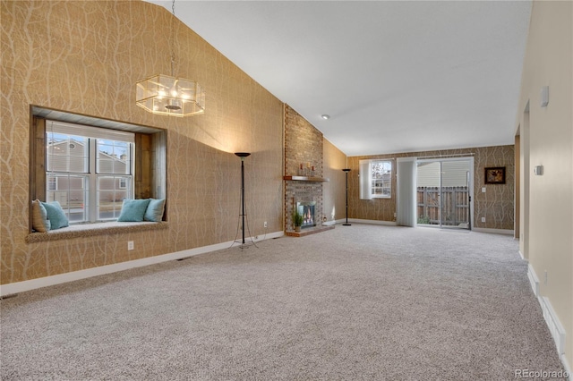 unfurnished living room featuring a healthy amount of sunlight, a brick fireplace, carpet, and high vaulted ceiling