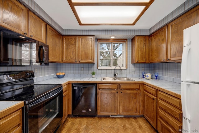 kitchen with tile countertops, black appliances, tasteful backsplash, and a sink