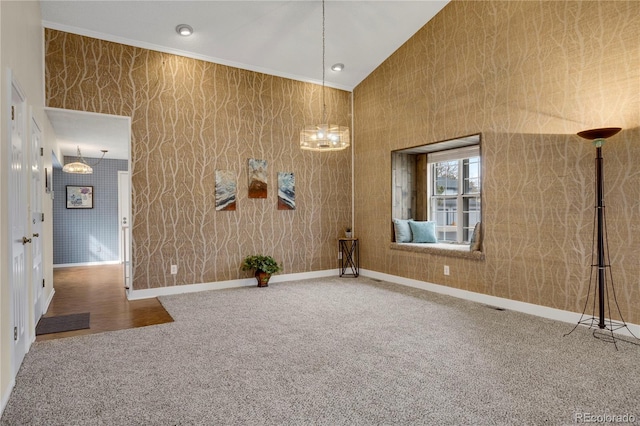 carpeted spare room featuring high vaulted ceiling, crown molding, baseboards, and a notable chandelier