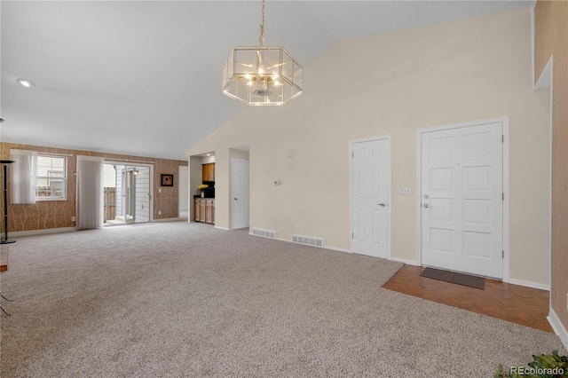 unfurnished living room with carpet floors, visible vents, high vaulted ceiling, and baseboards