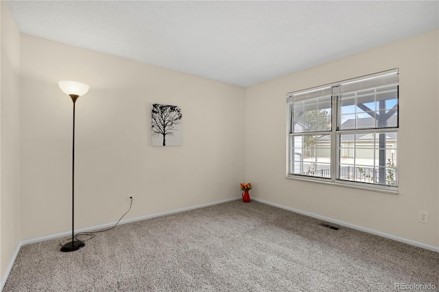 carpeted empty room featuring visible vents and baseboards