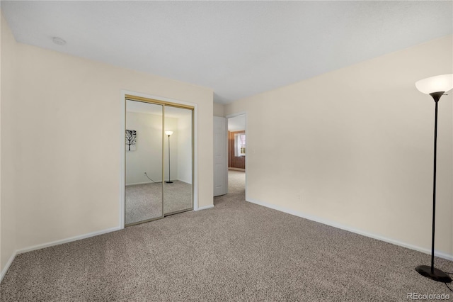 unfurnished bedroom featuring carpet floors, baseboards, and a closet