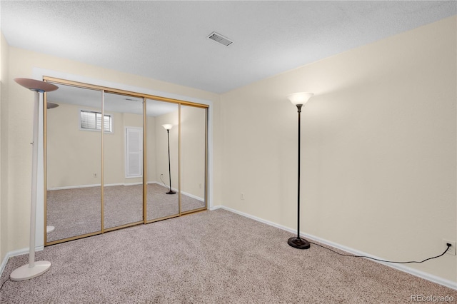 unfurnished bedroom with baseboards, a textured ceiling, visible vents, and carpet flooring