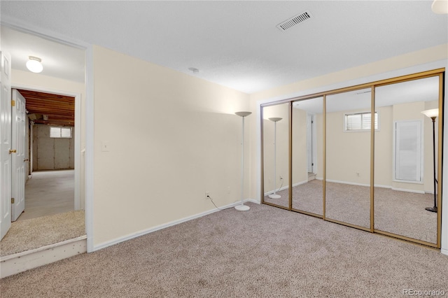 unfurnished bedroom with carpet floors, a closet, visible vents, and baseboards