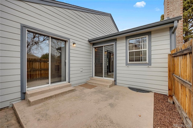 exterior space with entry steps, a chimney, fence, and a patio