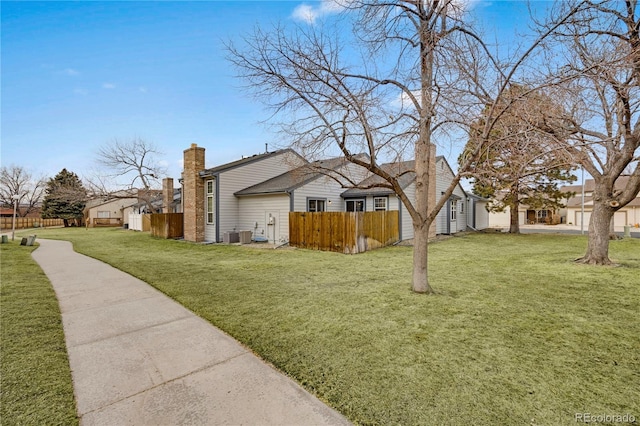 view of property exterior featuring fence, a chimney, and a lawn