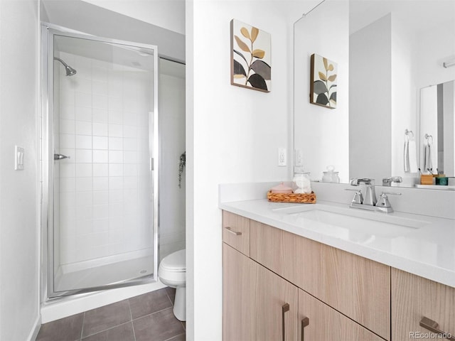 bathroom featuring vanity with extensive cabinet space, a shower with shower door, toilet, and tile floors