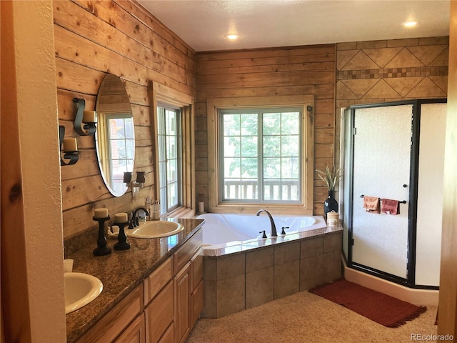 bathroom with dual vanity, wood walls, and plus walk in shower