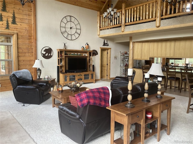 carpeted living room with wood walls, a chandelier, and a high ceiling