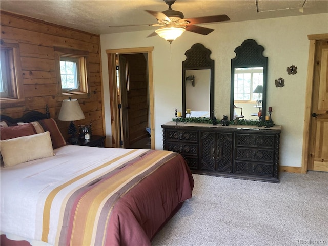 carpeted bedroom featuring wood walls, a textured ceiling, and ceiling fan