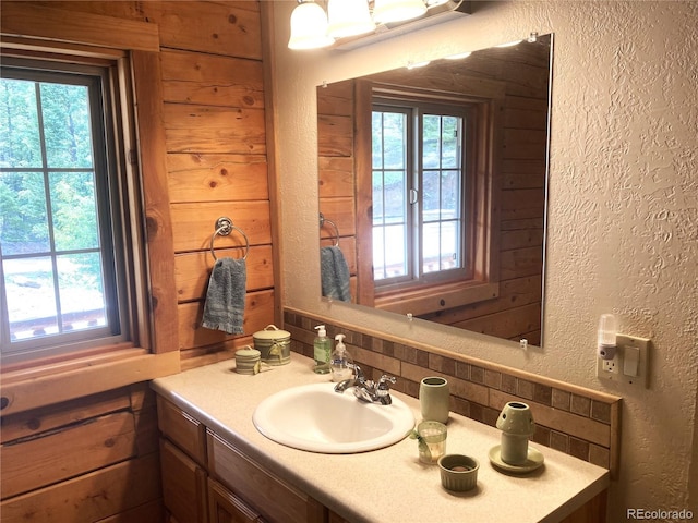 bathroom featuring wood walls, a wealth of natural light, and vanity