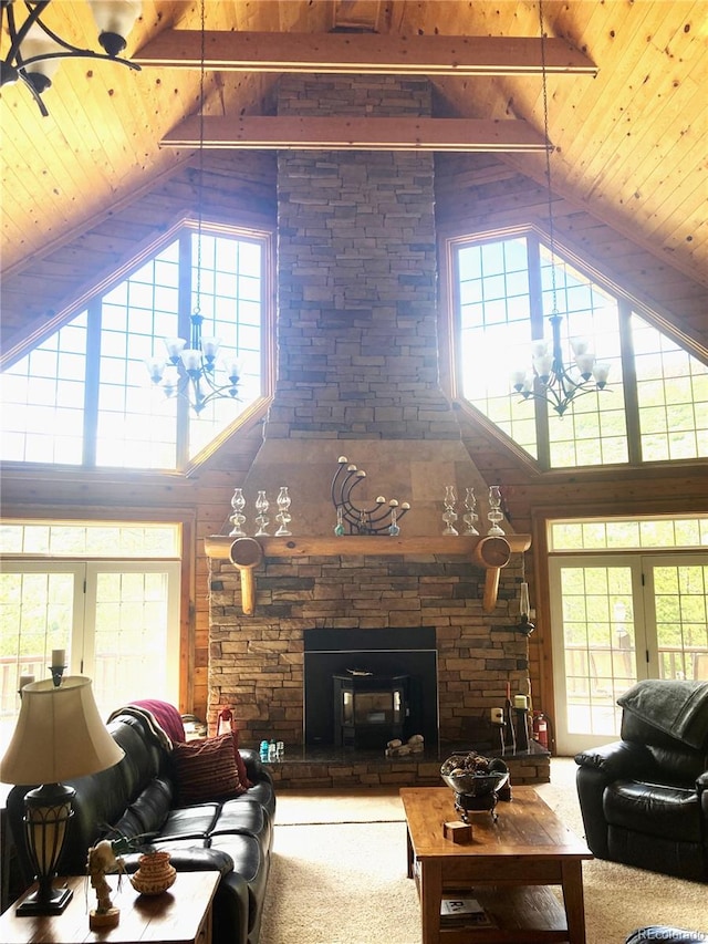 carpeted living room featuring beam ceiling, a stone fireplace, high vaulted ceiling, and wood ceiling