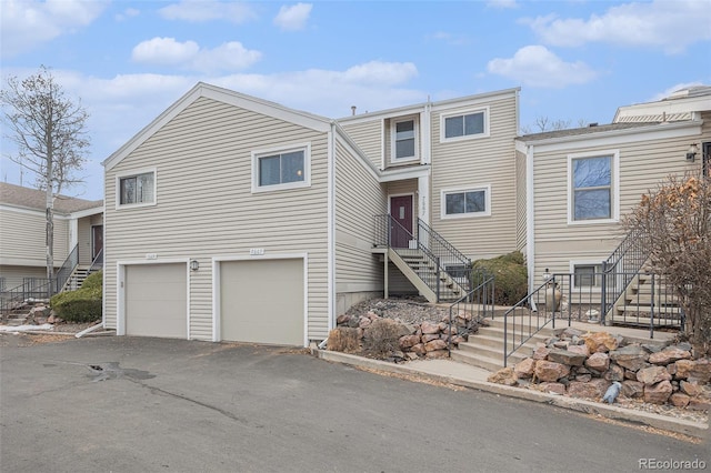 view of property with a garage, stairway, and aphalt driveway