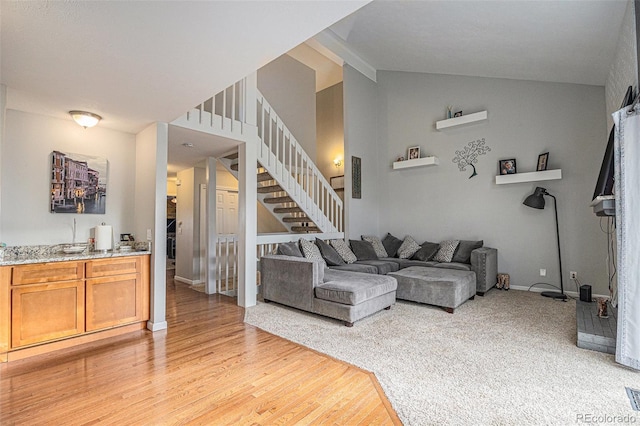 living area featuring vaulted ceiling, stairway, light wood-style flooring, and baseboards